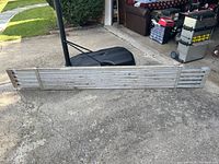 Aluminum scaffolding platform resting on concrete surface, showing full length and slotted design of the platform.