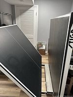 Black Stiga ping pong table folded upright showing top playing surface with white boundary lines.