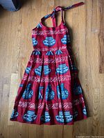 Front view of vintage linen halter dress laid flat, showing pottery print and halter tie.