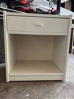 Front view of white nightstand showing one drawer and open shelf below
