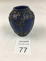Front-left side view of small cobalt blue glazed Moroccan vase with decorative metal overlay and round shape.
