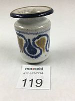 Front and slight angle view of small ceramic vase showing flared rim and colored overglaze decoration in blue and brown on grey base.