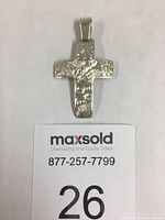 Front view of the sterling silver cross pendant showing wolf head, eagle, hawk engravings and paw prints.