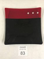Top view of the square fused glass dish showing the color contrast between black and ruby and the three white dots in the ruby section.