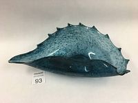 Side view of the teal blue blown glass conch shell bowl showing shape and color variation.