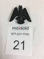 Top view of black resin Haida Thunderbird broach on white background with lot number card
