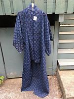 Full view of the blue-turquoise ikat kimono hanging outside, showing length and sleeve shape.