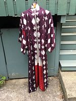 Front view of the full burgundy and white ikat kimono hanging on hanger outside