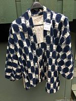 Front view of indigo and white checkered ikat jacket hanging on hanger showing jacket structure and style.