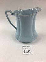 Front angle view of the light blue Johnson Brothers Greydawn pitcher showing ribbed body, scalloped rim with platinum trim, and handle.