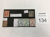 Full lot showing 8 stamps mounted on black card with handwritten notes describing each stamp type and origin.