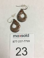 Pair of teardrop-shaped salmon earrings with etched copper design framed by silver, shown front side