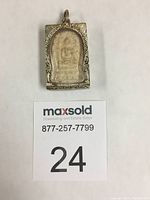 Front view of rectangular silver cased Thai amulet showing detailed Buddha seated figure on stone insert inside engraved silver frame with loop at top.