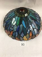 Angled side view showing color gradation from greens and blues downward to oranges and russets with visible cracks on glass pieces