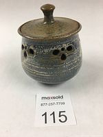 Front angled view of stoneware garlic pot with lid showing ventilation holes and lid knob