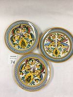 Top view of the three decorated Italian majolica plates arranged in a triangular layout showing hand painted colorful motifs and decorative borders.