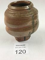 Photo showing front and side view of wood fired vase with earthy brown glaze and textured surface.