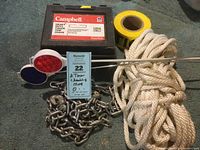 Photo showing two heavy-duty tow chains, nylon rope, yellow caution tape roll, and three round driveway reflectors (red and white).