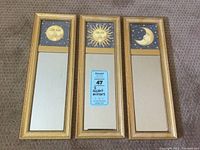 Set of three slim rectangular mirrors with gold-textured frames and celestial theme panels at the top showing sun, full moon, and crescent moon with stars.