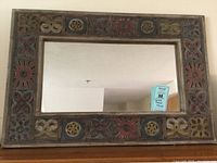 Front view of the rectangular carved frame mirror mounted on a wall showing the full frame design and mirror surface reflection.