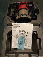 Electric router in molded plastic carrying case with owner's manual and a Maxsold tag, showing model number and brand clearly.