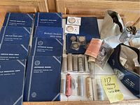 Six blue Whitman coin albums, paper rolls of cents, PCGS slabs with silver rounds, rolled foreign banknotes and coin pouches on table