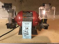 Front view of the Skil 3380 bench grinder with grinding wheel on left, wire brush on right, mounted on a shelf with protective covers above each wheel.