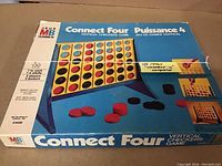 Full box image showing Connect Four vertical checkers game artwork and branding from the 1970s, including the MB Games logo and bilingual text.