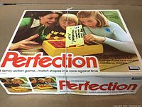 Full view of original 1975 Perfection game box with family image and game logo, showing condition of box lid.