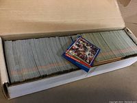 Photo of a large quantity of 1990 Donruss baseball cards stacked in a box with one card displayed on top.