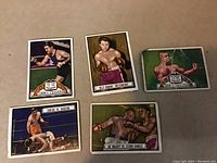 Five 1941 Topps Ringside boxing and wrestling cards laid on a table, showing front colorful portraits and action scenes of various fighters including Tommy Loughran and Billy Graham.