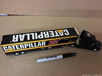 Full view of the diecast truck and trailer showing Caterpillar branding and Sharpie pen for size reference.
