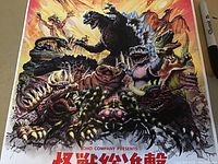 Close-up of detailed Godzilla and monster group artwork with vibrant colors and Japanese text at bottom.