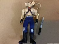 Full body view of the Biker Mice from Mars figure laying flat, next to a marker for size reference, showing wear and dirt marks.