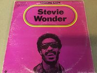 Front cover of the gatefold triple LP titled 'Looking Back' by Stevie Wonder showing a vibrant pink background with the artist's name and portrait.