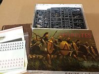 Open box showing multiple sprues with unassembled plastic Spartans model parts, decal sheets, and instruction manual.