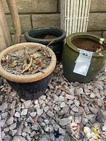 Three earthenware pots on gravel ground outdoors showing their general shape and color variations.
