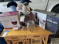 Photo showing Rabbit electric wine set box, Mozaik stemless wine glasses box, Allen & Roth solar lantern jar and other small items on a wooden table.