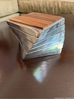 Side view showing the twisted metal alloy sides and wooden top of stacked coasters.