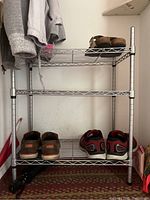 Front view of the 3-tier metal shoe rack with various shoes on the shelves, showing wire wire shelves and vertical supports.