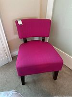 Photo of hot pink upholstered chair showing front and seat angle, highlighting fabric texture and wooden legs.