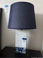Full view of table lamp showing dark fabric shade and white marble base with blue stone accents