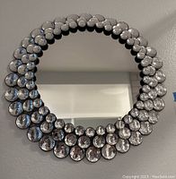 Full view of round wall mirror with concentric faux jewel frame on wall