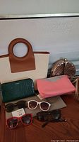 Photo depicting the assortment of bags, Aldo wallet, and four pairs of sunglasses arranged on a wooden surface.
