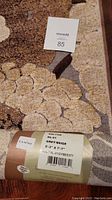 Close up of the rug edge showing the color and wear on corner with a label attached indicating brand, model and size.