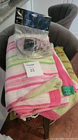 Umbra towel ring in sealed package on top of folded colorful beach towel and cushion on chair
