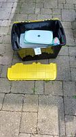 Large storage bin with yellow lid detached showing inside container assortment