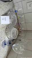 Martini glasses with colored stems arranged in line next to cut crystal ashtrays and bowl on a countertop