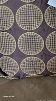 Silky cushion fabric with circular beige houndstooth pattern on a dark brown background