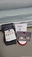 All five pairs of costume earrings shown on display cards and on a gray surface with a MaxSold lot card